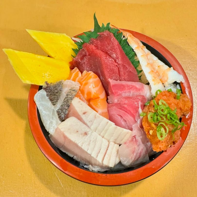 A colorful Akita Japanese Restaurant chirashi bowl with various sashimi, tamago, and shrimp.